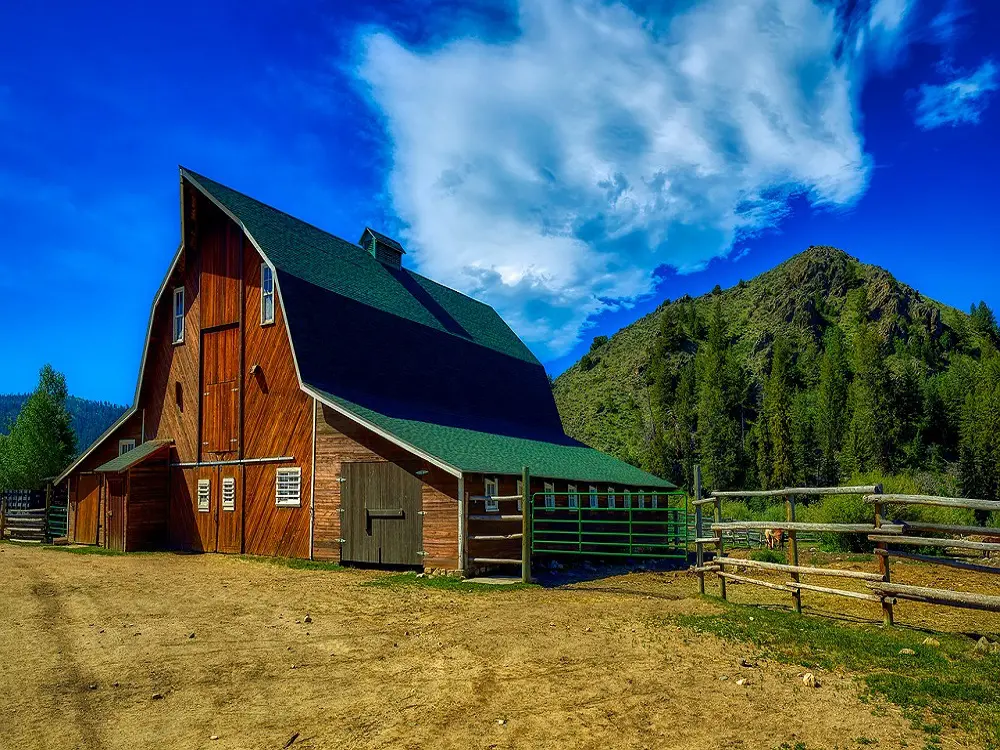 A barn with a green roof and a fence